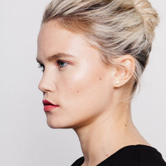 Blonde female model wearing a pair of matthew calvin dot stud earrings