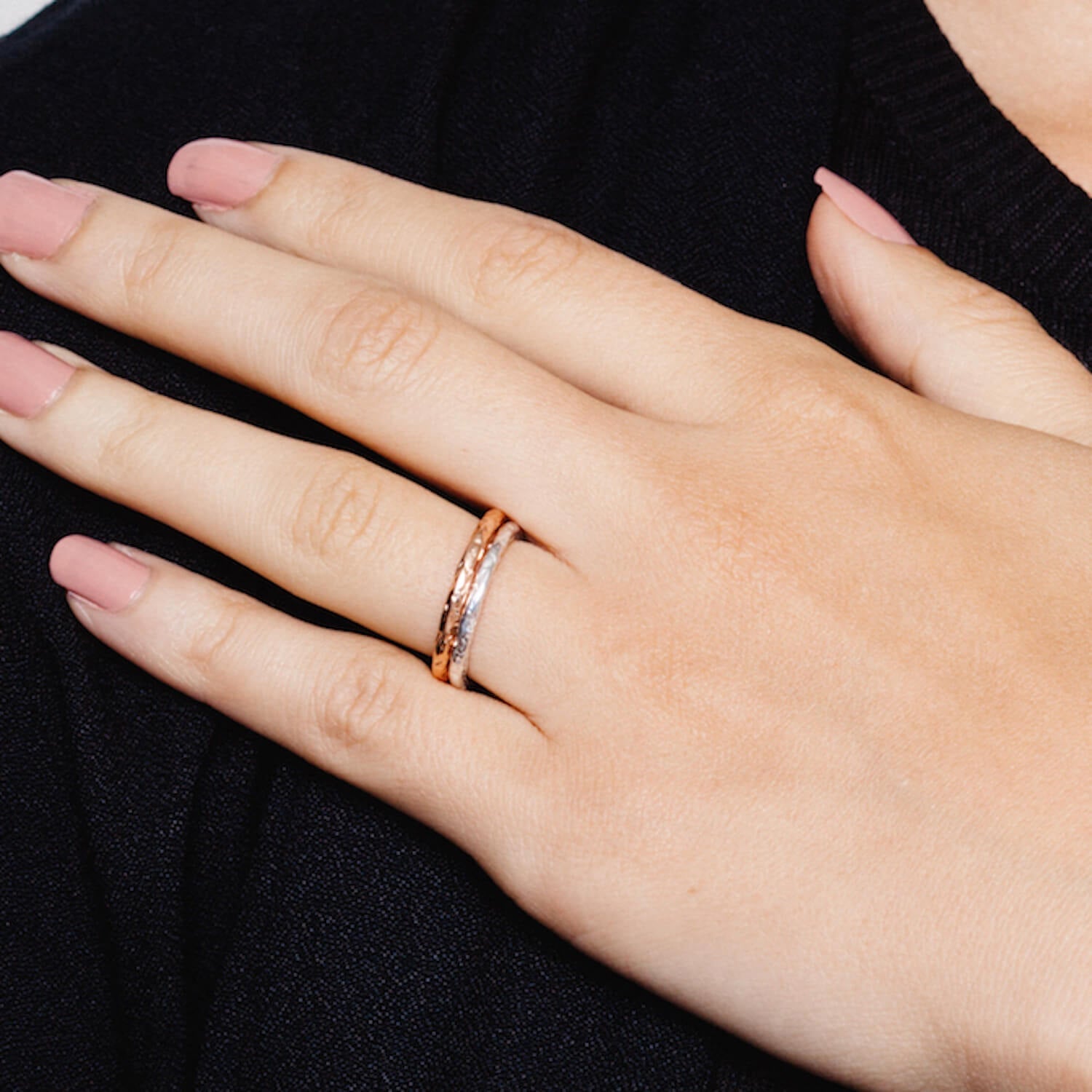 Woman's hand wearing two Matthew Calvin rings with a meteorite style hammered finish