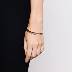 A woman wearing two textured bangles, one in silver, one in gold