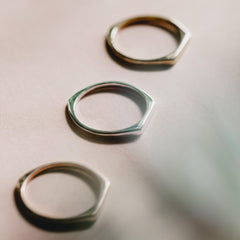 Close up of three rings, all thin signet rings, in different colours