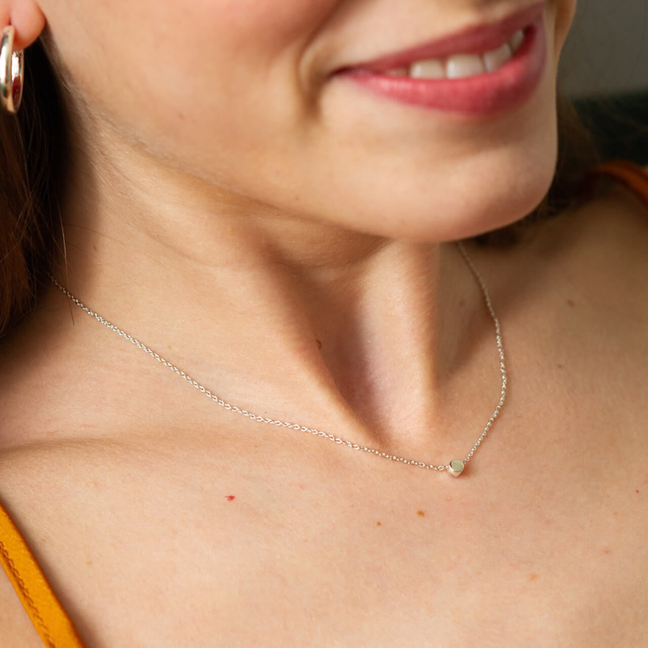 Close up of a female model's neck wearing the silver dot necklace by matthew calvin