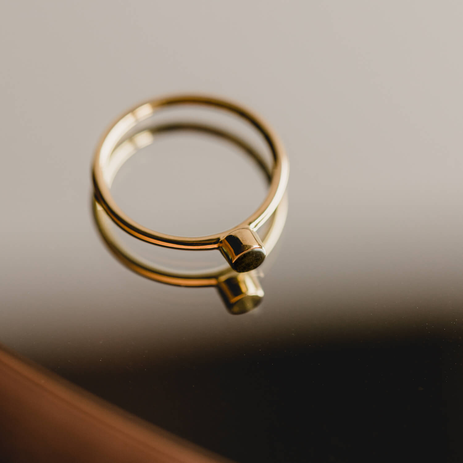 Dark and shadowy image of a gold Matthew calvin dot ring on a mirror