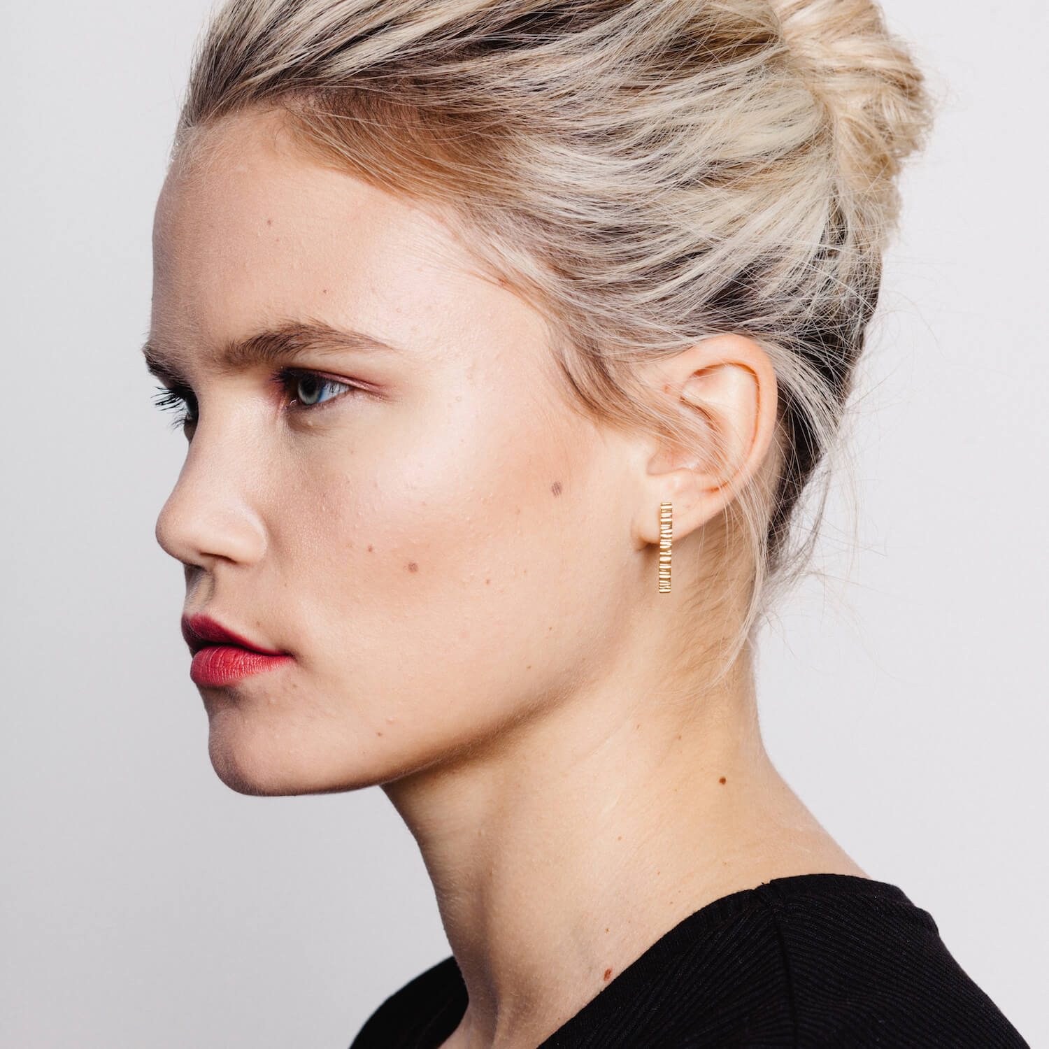 Woman wearing rose gold long bar earrings with a textured finish