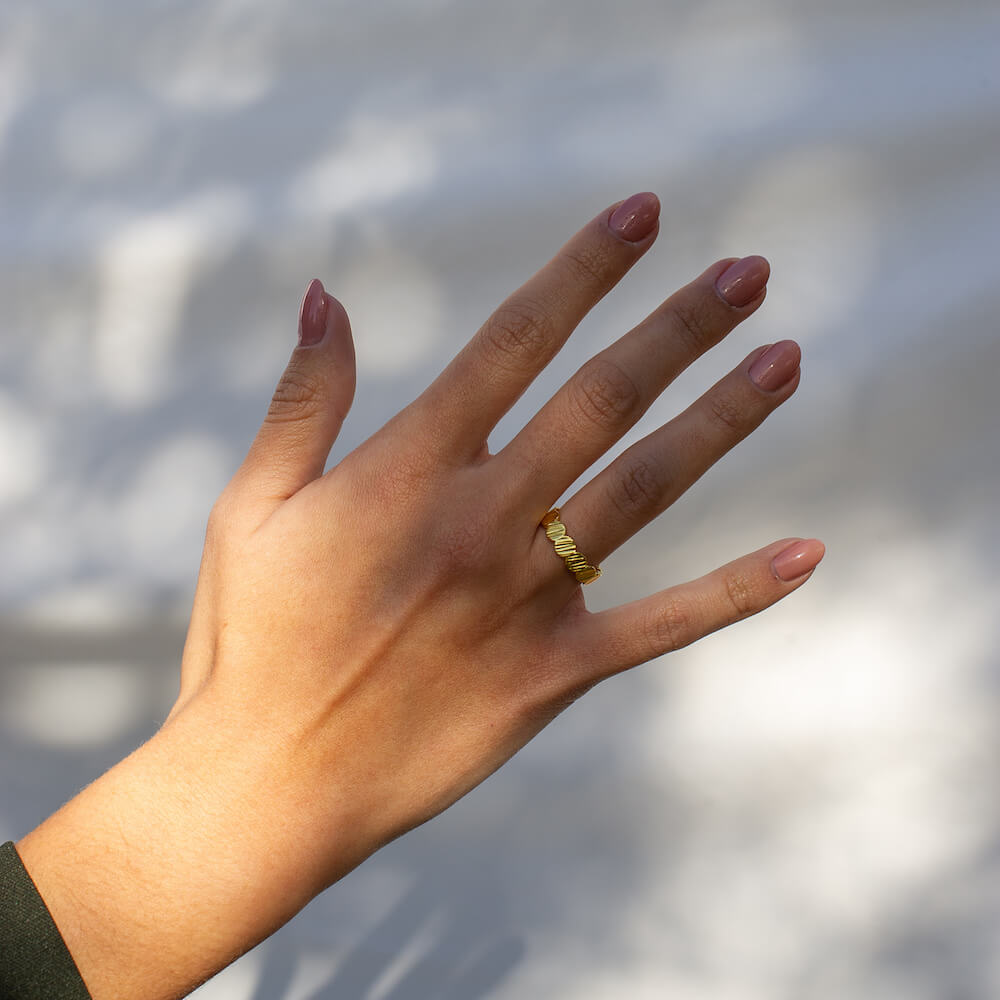 A hand wearing a Charm Ring in gold by Matthew Calvin