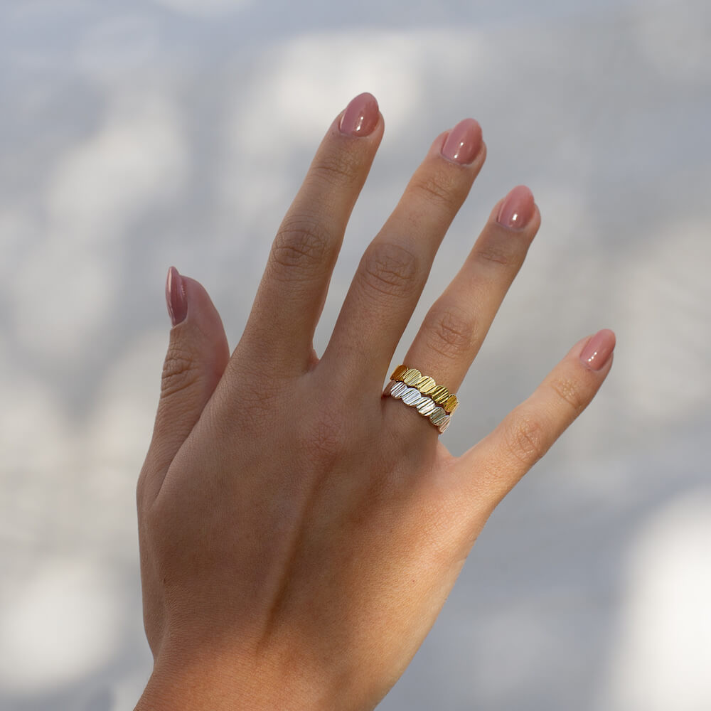 A model wearing two rings on her hand, one in solid sterling silver and one in gold