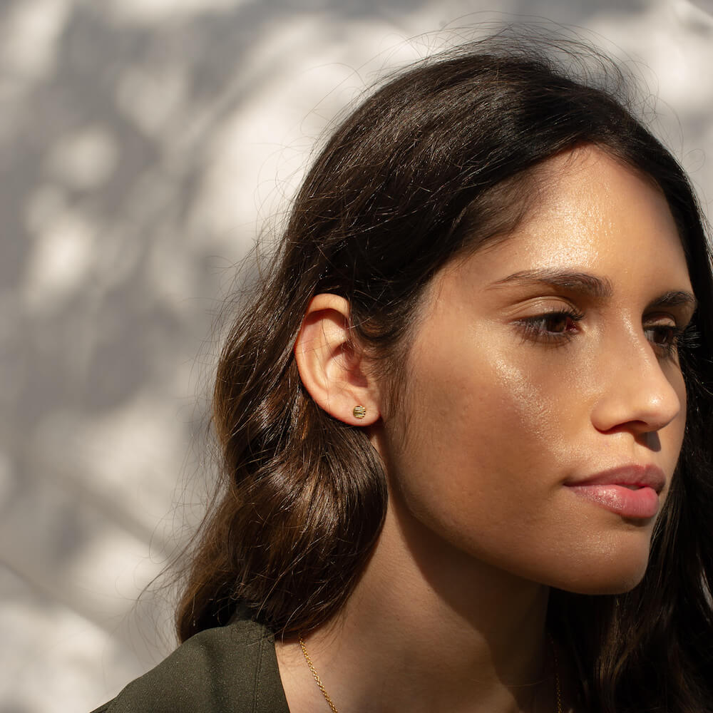 Model wearing gold Origins Studs with an uneven textured effect