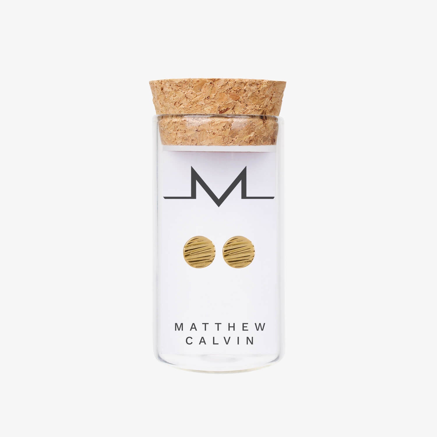 A glass bottle with a cork lid which has round gold earrings displayed in it