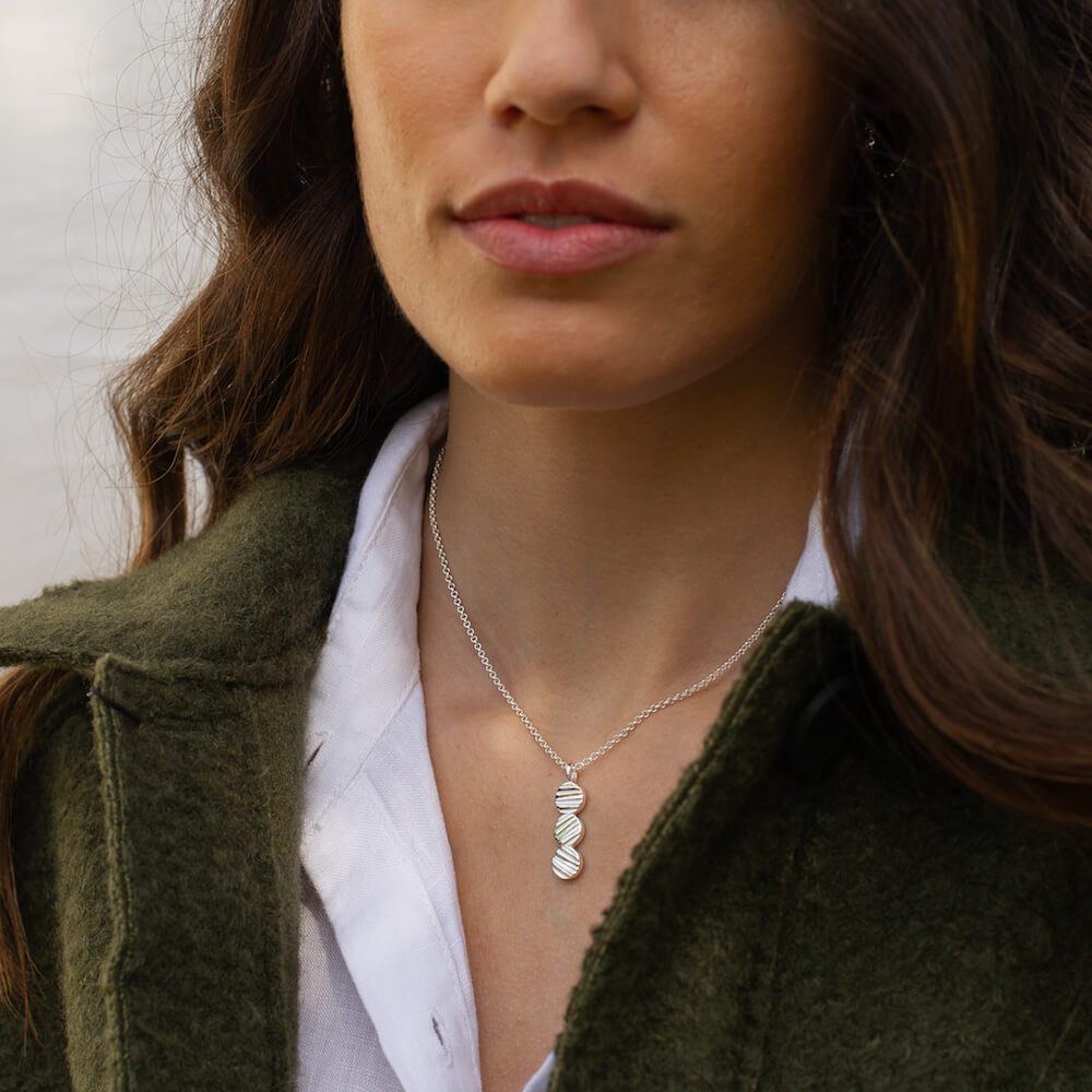 A woman wearing a silver pendant with an asymmetric textured detail