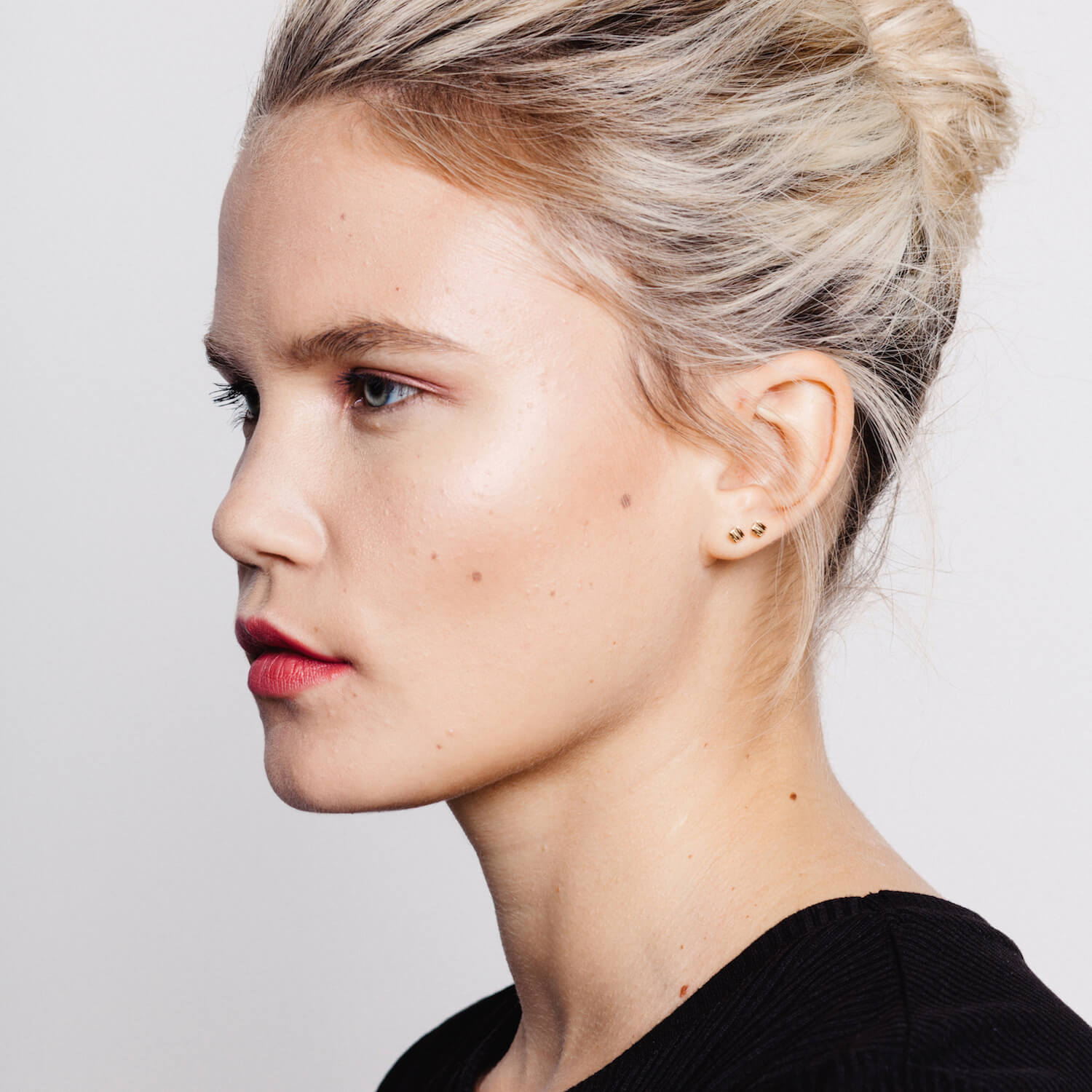 A woman wearing a pair of small square studs with textured finish