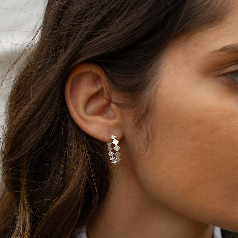 A woman wearing a spiky silver hoop with textured detailing