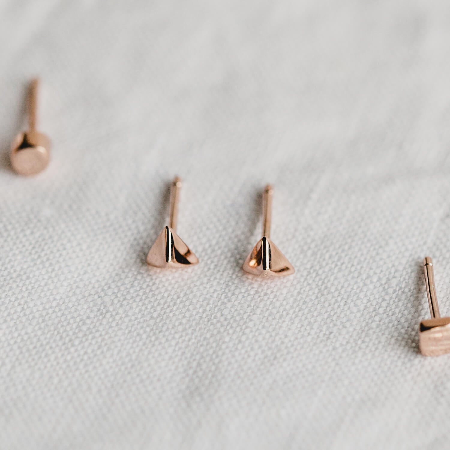 Close up of stud earrings with a geometric triangle shape