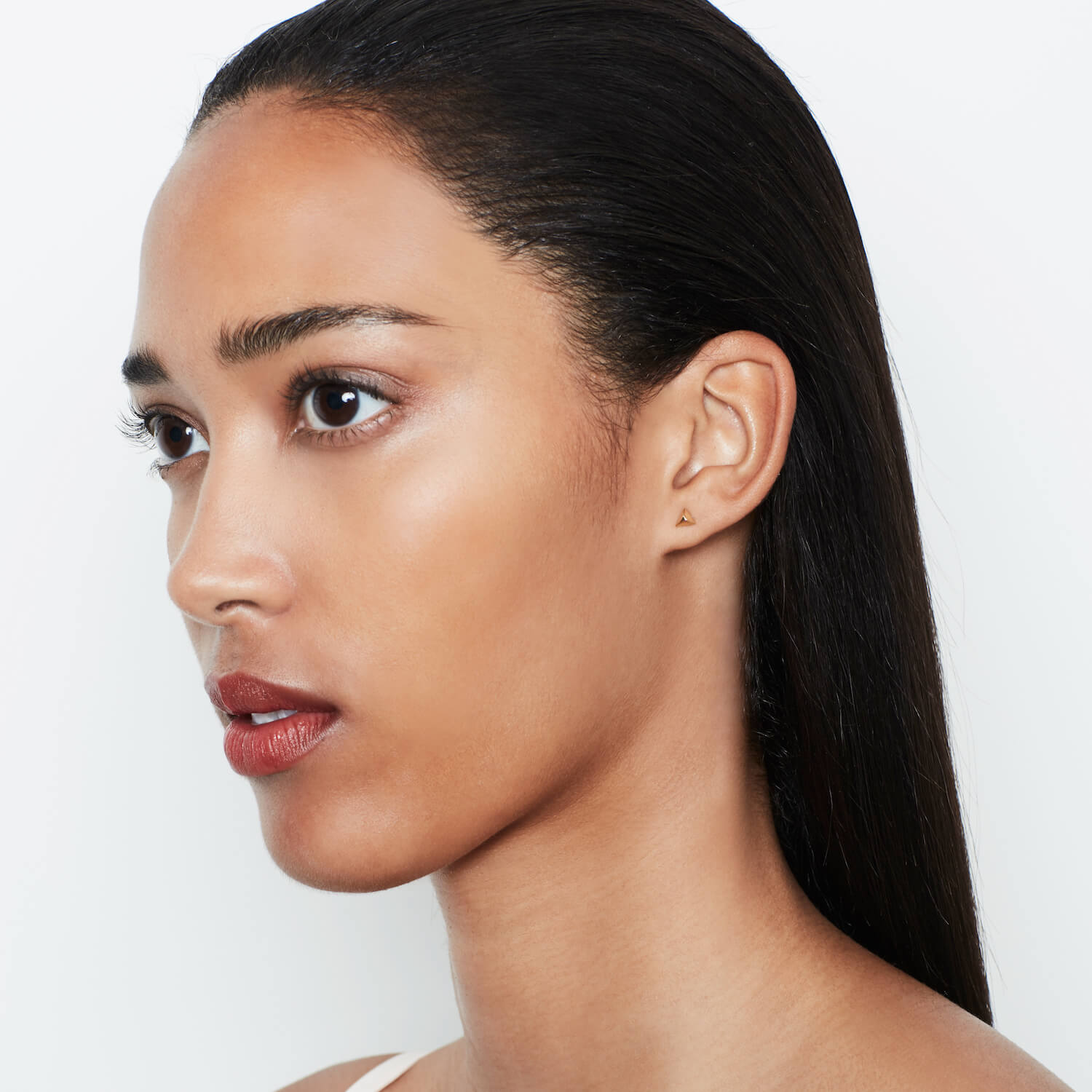 Model wearing small gold studs in the shape of a pyramid