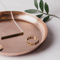 A rose gold beaded ring on a rose gold dish
