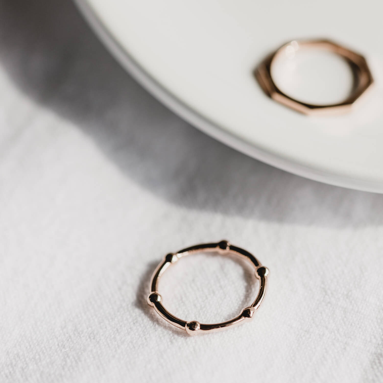 A beaded wire ring made from rose gold and a hexagonal shaped ring made from rose gold
