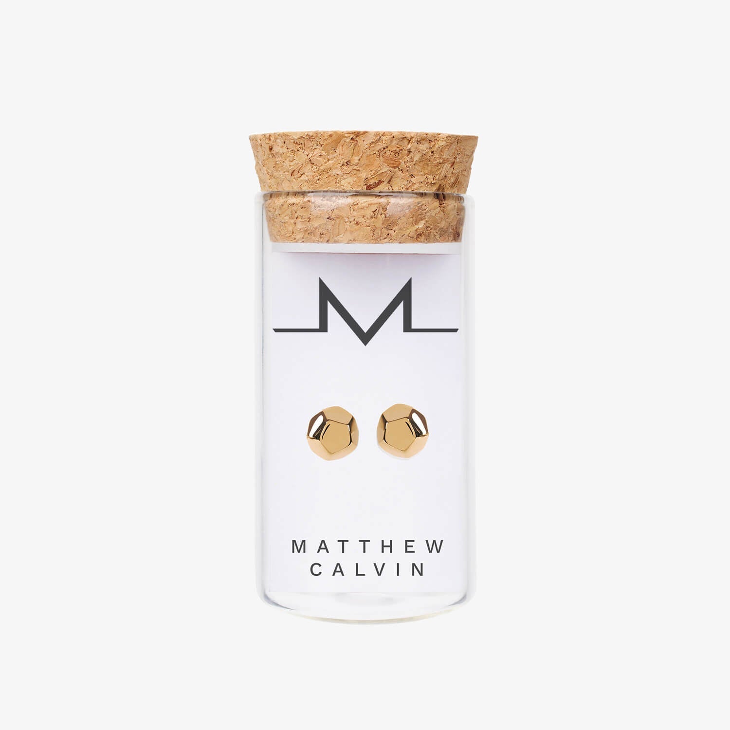 Matthew Calvin gold dodecahedron shaped stud earrings in a glass tube with cork top. 
