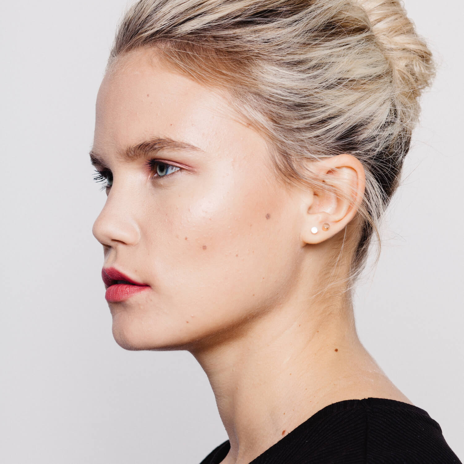 Blonde female model wearing two pairs of matthew calvin dot stud earrings