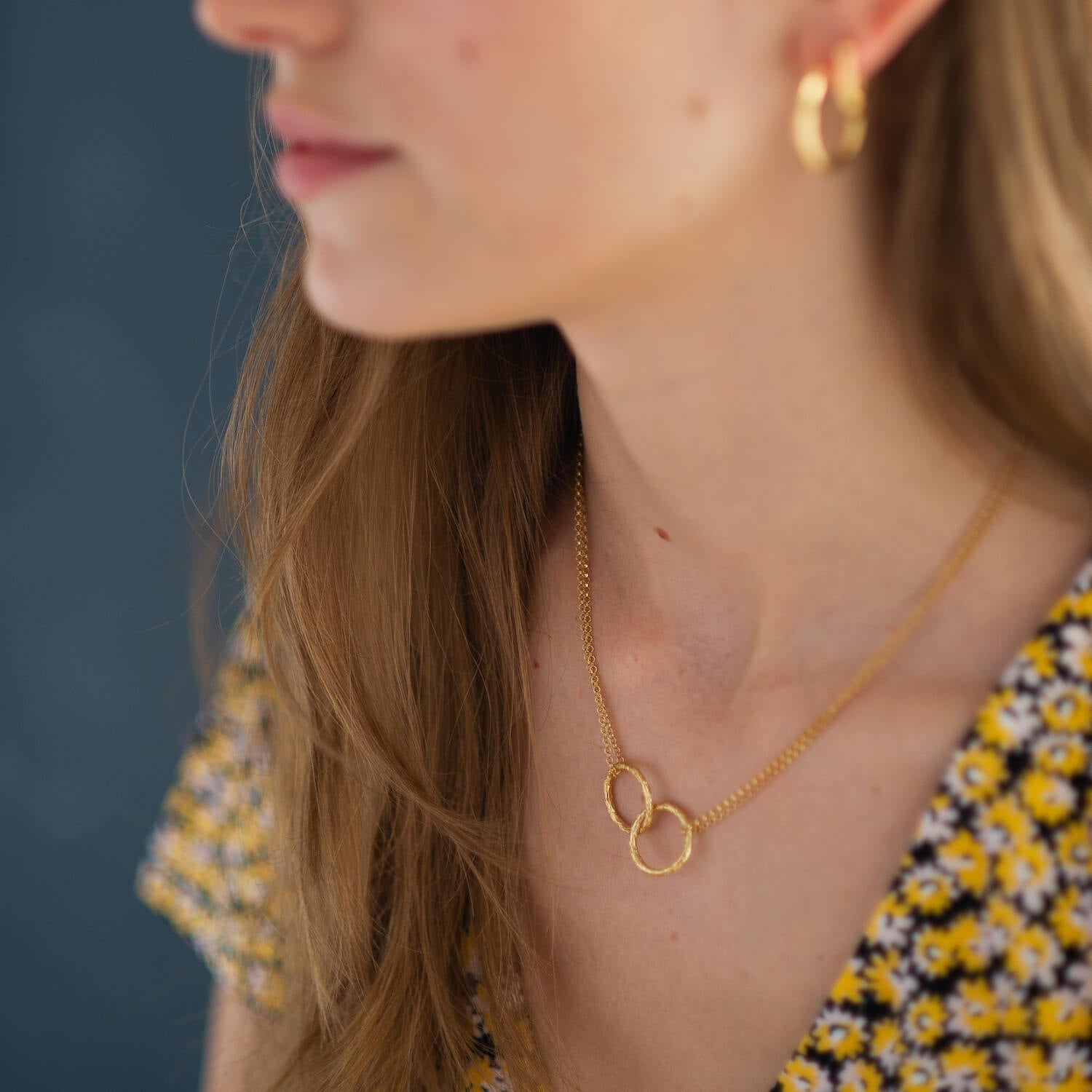 Woman wearing necklace with two joined rings in gold