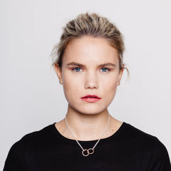 Model wearing pendant with two intertwined rings in rose gold