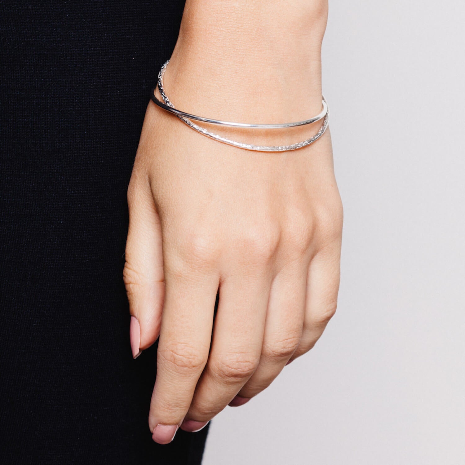 Close up of model wearing intertwined silver bangles