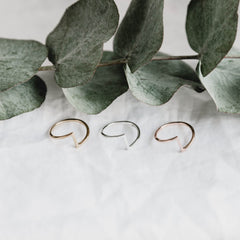 Trio of Matthew Calvin joint rings in gold, rose gold and silver with green eucalyptus leaves