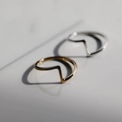 Pair of matthew calvin joint rings in silver and gold photographed on a shiny white surface with harsh shadows