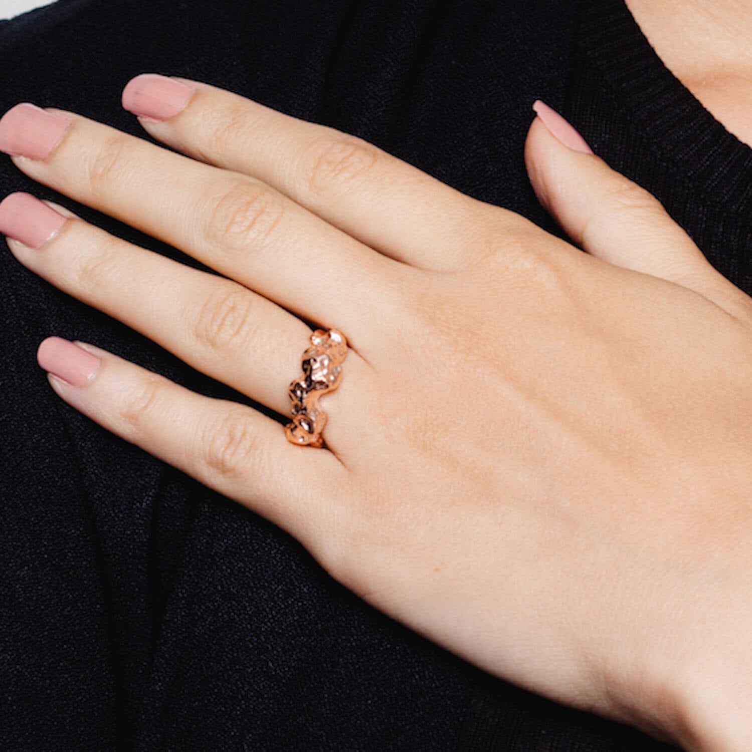Close up of hand with heavily textured meteor ring in rose gold
