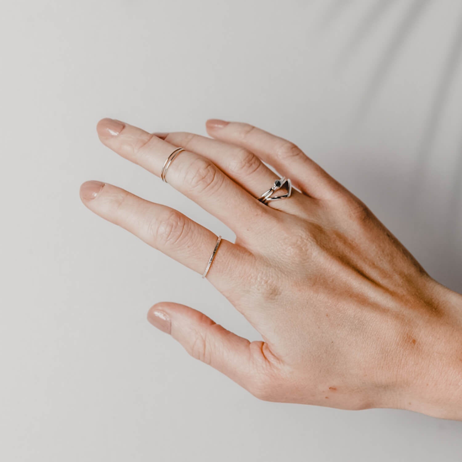 Close up of a woman's hand wearing multiple Matthew Calvin rings