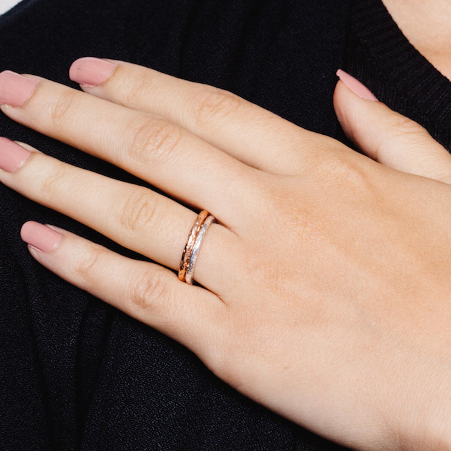 A close of a model's hand with two Matthew Calvin rings on, both with a hammered effect