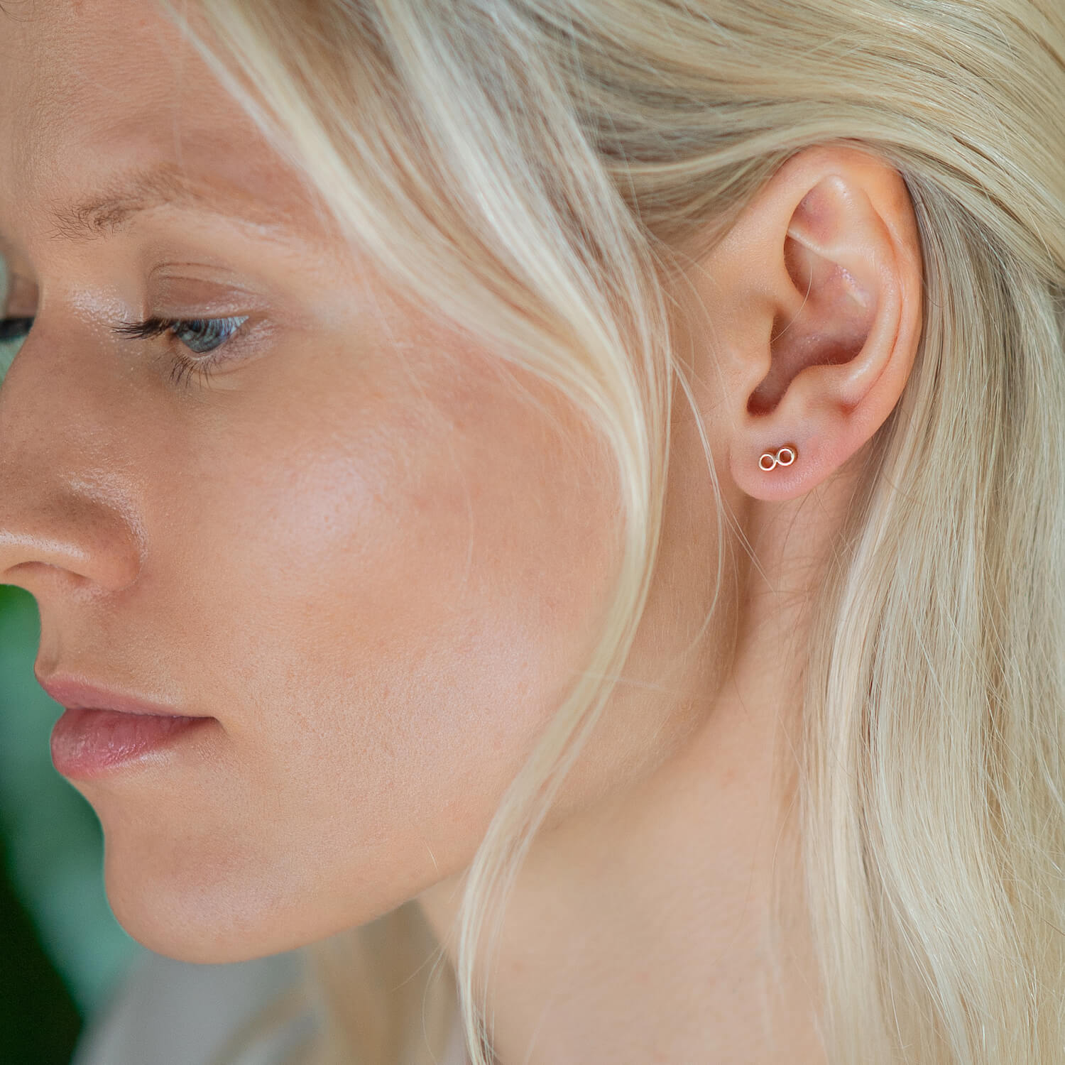 Female, blonde model wearing Matthew Calvin tiny double tube earrings in gold.