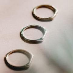 Close up of three thin signet rings, one in rose gold, one in gold and one in silver