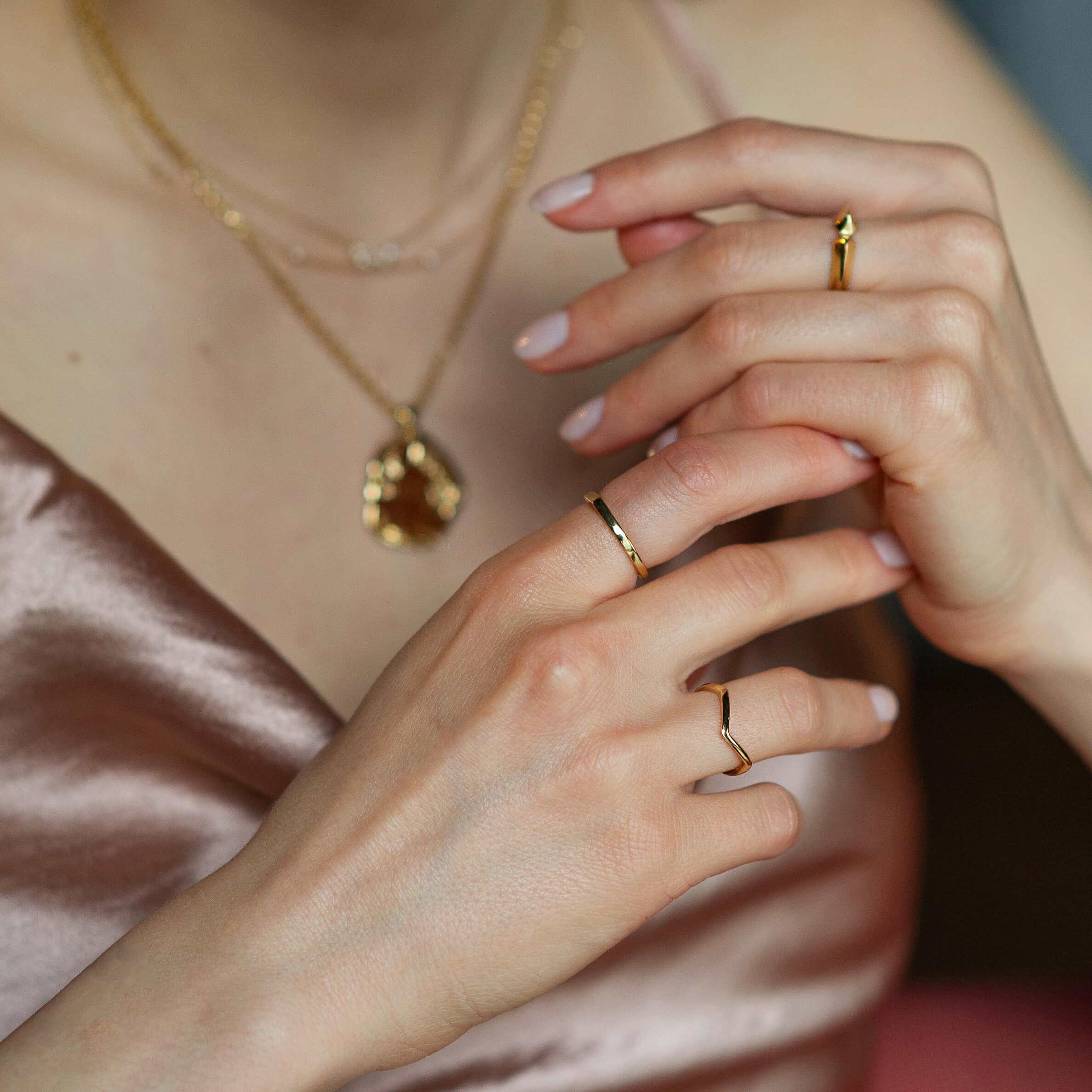 A woman wearing multiple pieces of gold jewellery including a necklace and three rings
