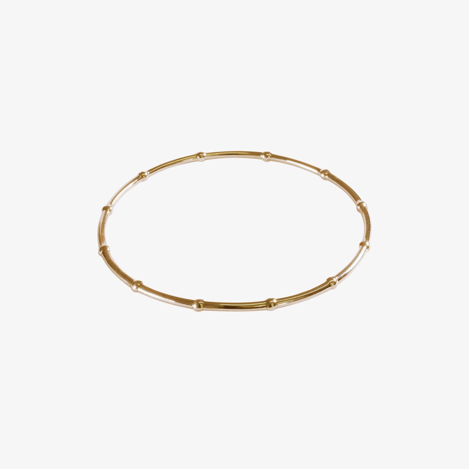 Gold bangle made from beaded wire on a white background