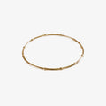 Gold bangle made from beaded wire on a white background