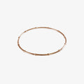 A rose gold bangle made of beaded wire on a white background
