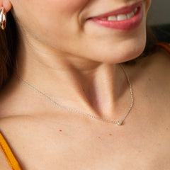 Close up of a female model's neck wearing the silver dot necklace by matthew calvin