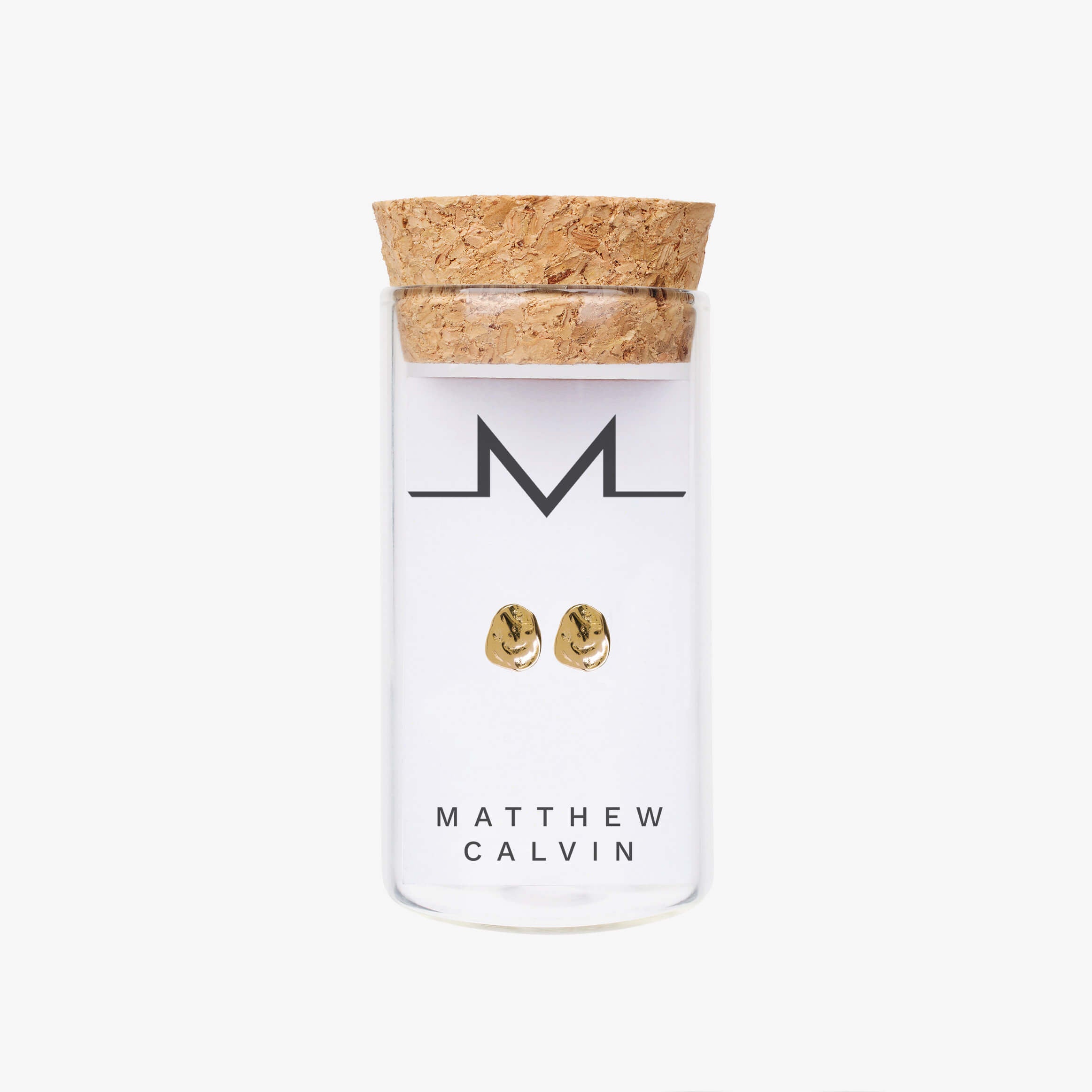 small gold nugget dappled stud earrings by matthew calvin presented in a glass tube with cork stopper on a white background