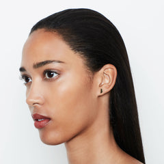 A model wearing small disc shaped stud earrings