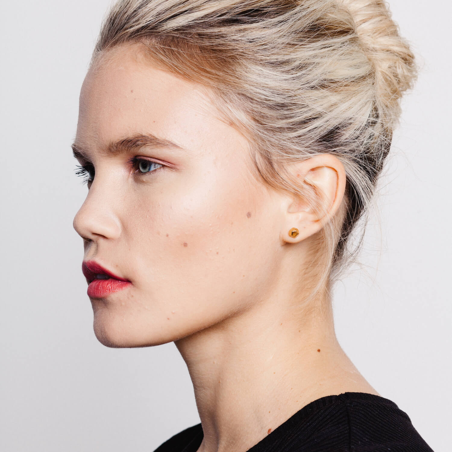Model wearing gold dodecahedron stud earrings by matthew calvin