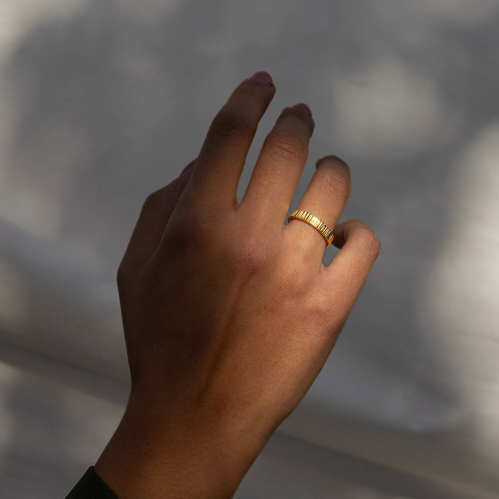 Model's hand wearing textured gold ring
