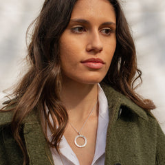 A woman wearing a textured silver circular necklace