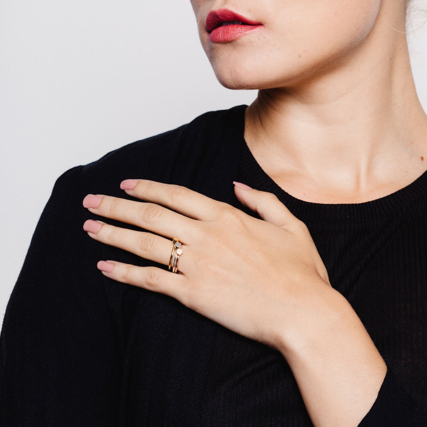 Model wearing three stacked Matthew Calvin dot rings, in silver, gold and rose gold