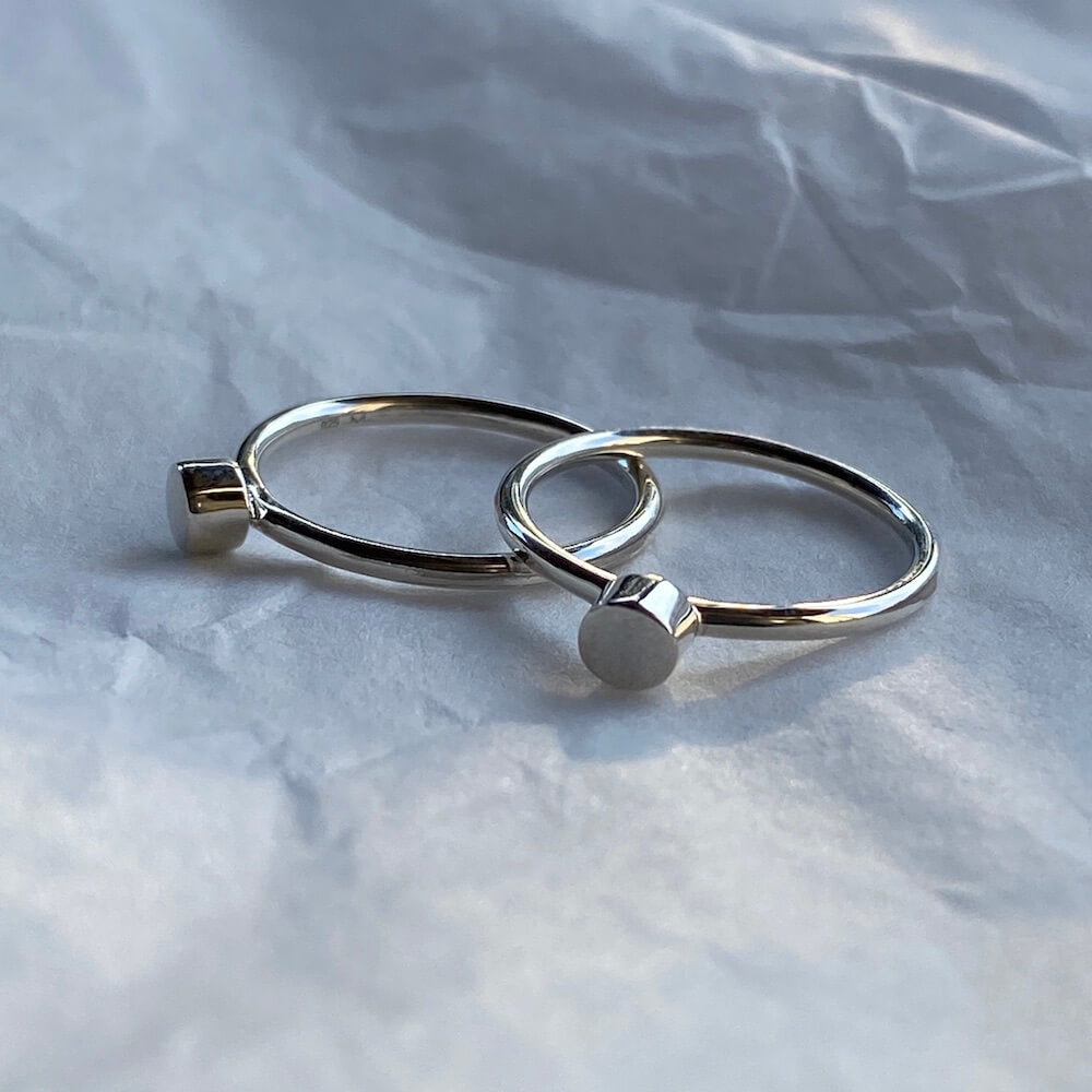 Pair of Sterling silver circle Matthew Calvin dot rings on a white background