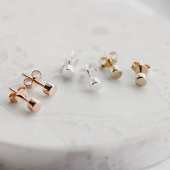Rose gold, silver and gold dot stud earrings in a row on a terrazzo tile