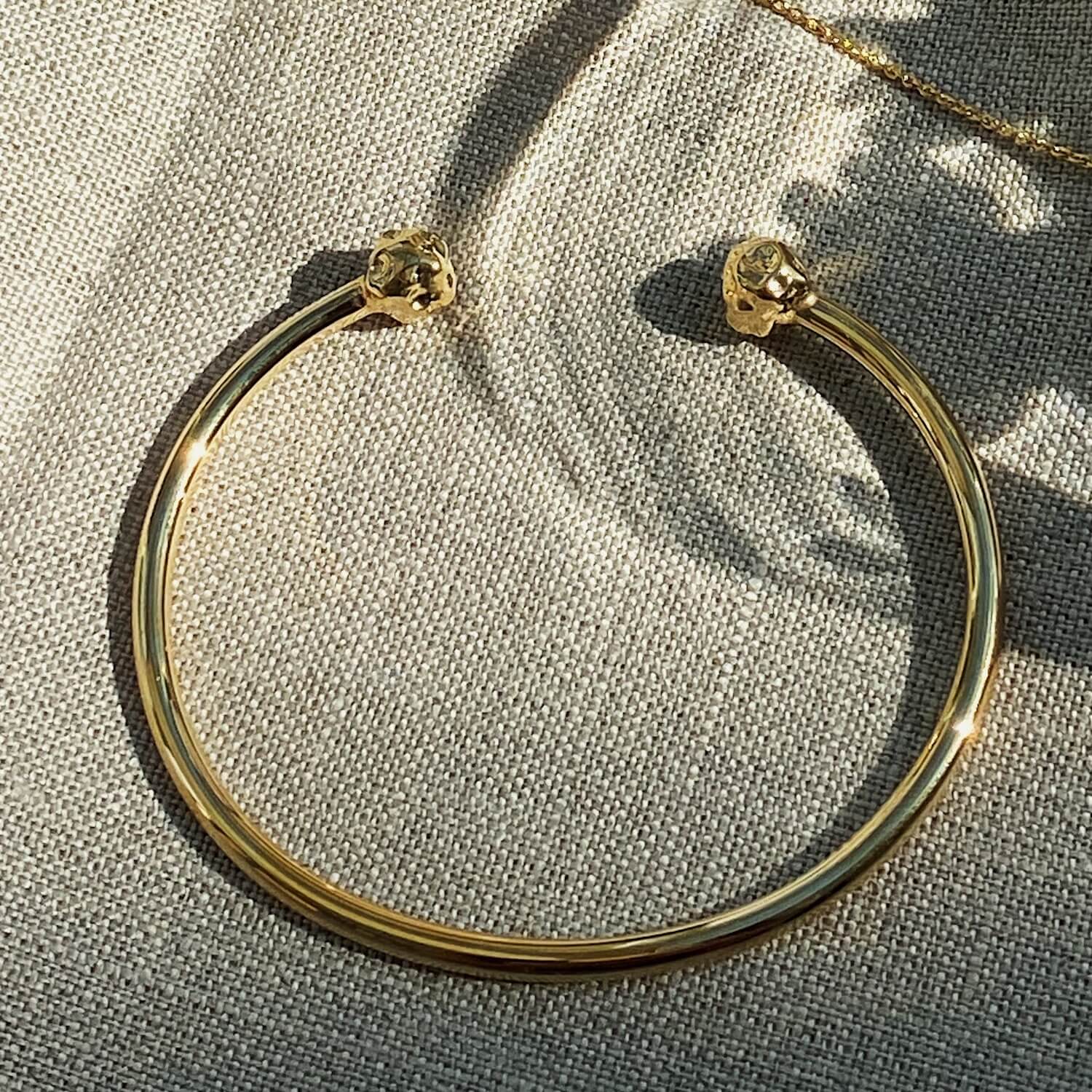Close up of gold open bangle with textured charms