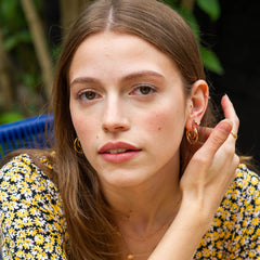 Model wearing earrings including hoops with meteorite texturing