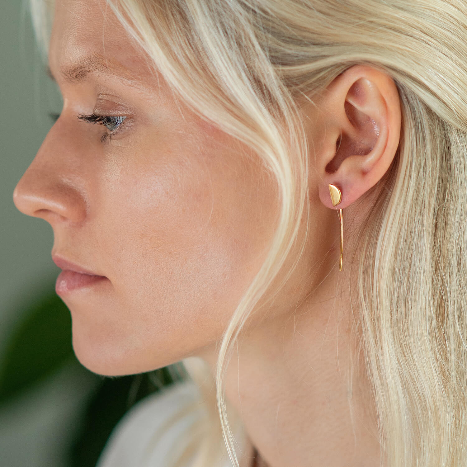 Woman wearing dropback earrings with a disc shaped charm