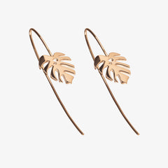 Two rose gold dropback earrings with monstera charms on a white background