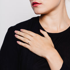 Close up of a model wearing two textured rings, one in silver and one in gold