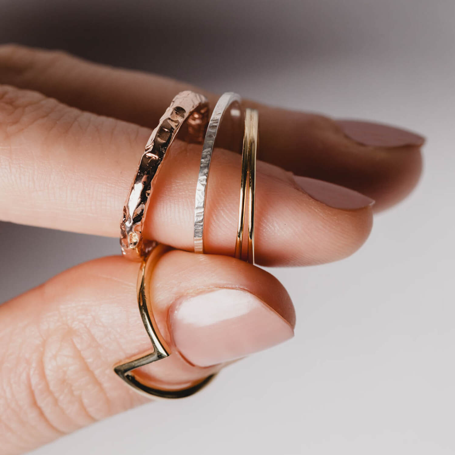 Close up of a hand holding several rings in various colours and styles