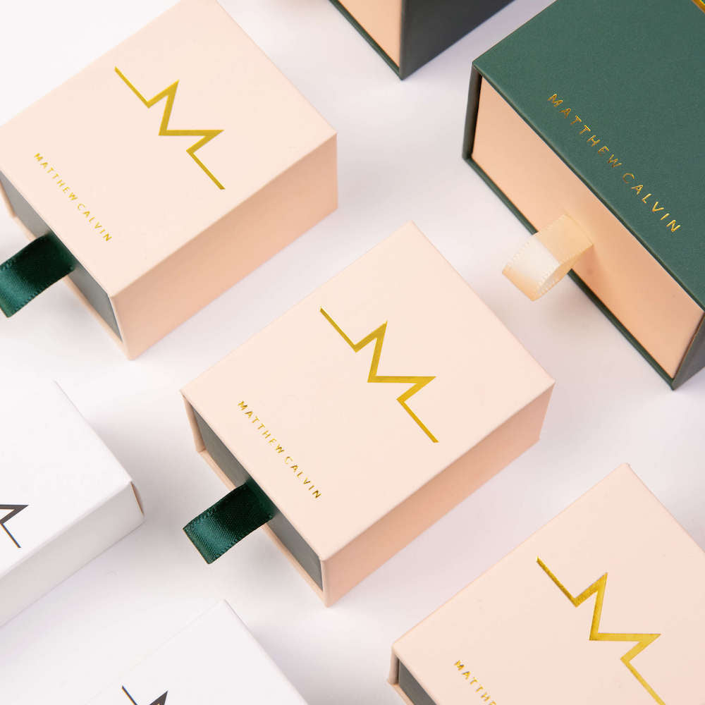 Jewellery boxes in pink and green with gold writing which says Matthew Calvin